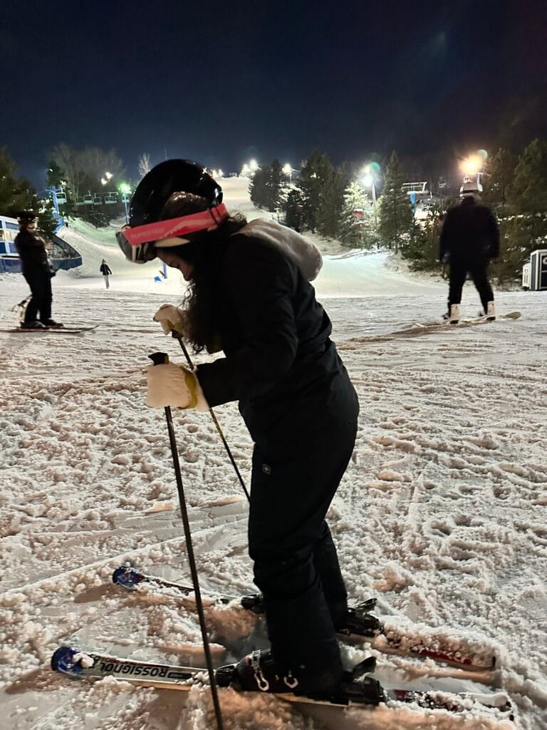 Angélica Madrid esquiando de noche en una pista nevada, con equipo completo de invierno.