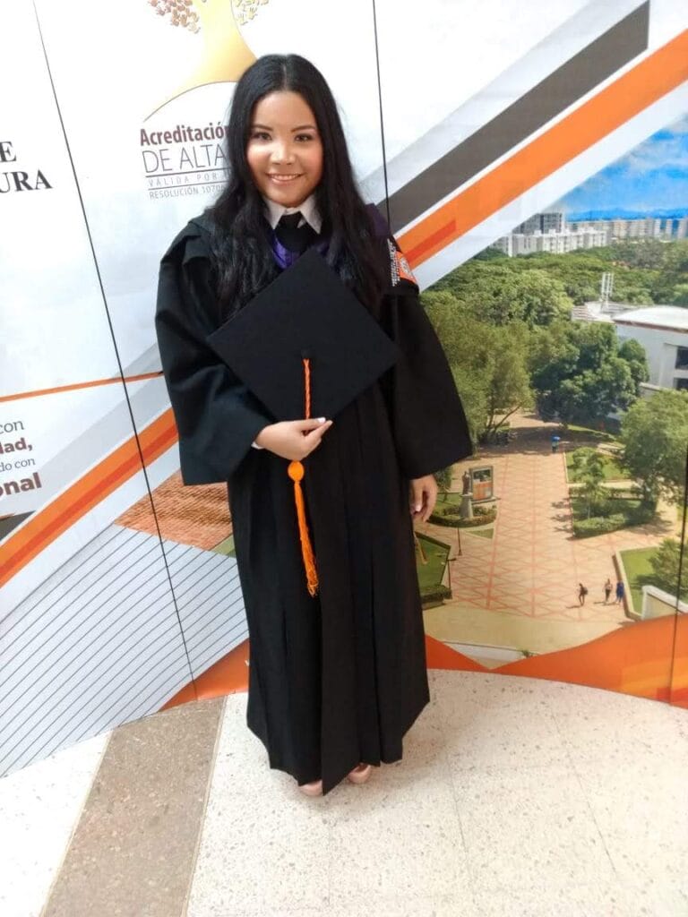 Angélica Madrid el día de su graduación como psicóloga, sosteniendo el birrete y sonriendo.