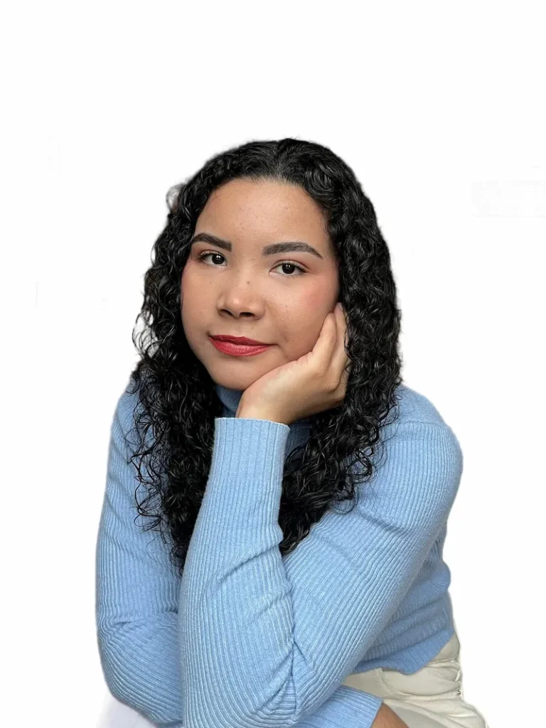 Angélica Madrid, escritora de Crónicas del Reino Oscuro Retrato de Angélica Madrid, autora de Crónicas del Reino Oscuro, sentada con expresión amigable y blusa azul.